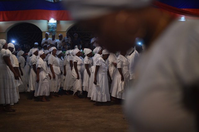 Haitian voodoo followers wearing white clothes dance while participating in a voodoo ceremony in Souvenance, a suburb of Gonaives, 171km north of Port-au-Prince, on March 31, 2018. Haitian voodoo followers arrived in Souvenance to take part in the voodoo ceremonies held during Easter weekend. / AFP PHOTO / Hector RETAMAL