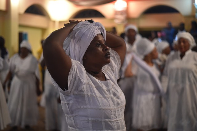 Haitian voodoo followers wearing white clothes participate in a voodoo ceremony in Souvenance, a suburb of Gonaives, 171km north of Port-au-Prince, on March 31, 2018. Haitian voodoo followers arrived in Souvenance to take part in the voodoo ceremonies held during Easter weekend. / AFP PHOTO / Hector RETAMAL