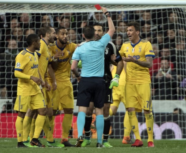 El árbitro inglés Michael Oliver (4L) leyó una tarjeta al portero italiano Juventus Gianluigi Buffon (2R) durante el partido de fútbol de cuartos de final de la UEFA Champions League entre Real Madrid CF y Juventus FC en el estadio Santiago Bernabéu de Madrid el 11 de abril , 2018.  CURTO DE LA TORRE / AFP