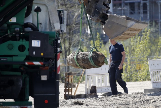 Un policía alemán observa que una bomba lanzada durante la Segunda Guerra Mundial fue levantada con una excavadora durante la operación de eliminación el 20 de abril de 2018 en Berlín. Miles de personas alrededor de la estación central de trenes de Berlín fueron evacuados mientras los expertos en desactivación de explosivos desactivaron un explosivo sin explotar de la Segunda Guerra Mundial desenterrado en una obra en el distrito Mitte de Berlín. / AFP PHOTO / Odd ANDERSEN