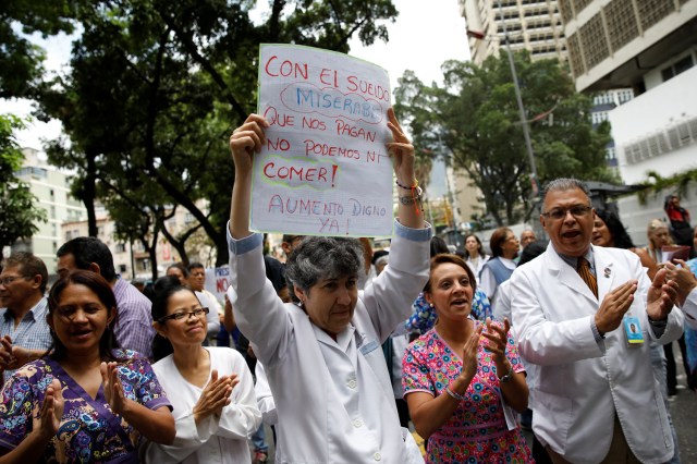 Workers of the health sector take part in a protest due to the shortages of basic medical supplies and for higher wages outside a children hospital in Caracas, Venezuela April 17, 2018. The placard reads, "With the miserable salary they pay us, we can not even eat. A worthy increase, now". REUTERS/Carlos Garcia Rawlins