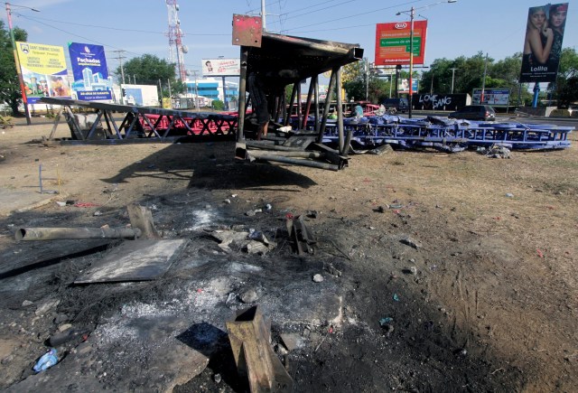 Hombres cortaron cables y piezas de metal para vender en el mercado del árbol de acero del gobierno nicaragüense (Life Trees) incendiados durante una protesta contra las reformas del gobierno en el Instituto de Seguridad Social (INSS), en Managua el 22 de abril de 2018. Las violentas protestas contra un cambio propuesto en el sistema de pensiones de Nicaragua dejaron al menos 20 muertos, según un organismo local de derechos humanos. El Centro Nicaragüense de Derechos Humanos dijo que aún estaba tratando de verificar las cifras, pero que al menos 20 personas habían muerto desde que estallaron las protestas en el país centroamericano el 18 de abril por la reforma de las pensiones. / AFP PHOTO / INTI OCON