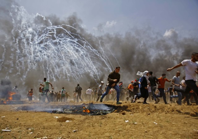 Los palestinos huyen del gas lacrimógeno durante los enfrentamientos con las fuerzas de seguridad israelíes cerca de la frontera entre Israel y la Franja de Gaza, al este de Jabalia el 14 de mayo de 2018, mientras los palestinos protestan por la inauguración de la embajada de Estados Unidos tras su controvertido traslado a Jerusalén. / AFP PHOTO / MOHAMMED ABED