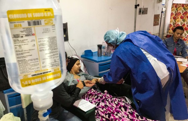 A girl is assisted by a nurse at the chemotherapy room of the "Dr. JM de los Rios" Children's Hospital in Caracas on April 10, 2018. The crisis in Venezuela has hit children's health, with an increase of 30,12% in child mortality according to the most recent official sources. / AFP PHOTO / FEDERICO PARRA