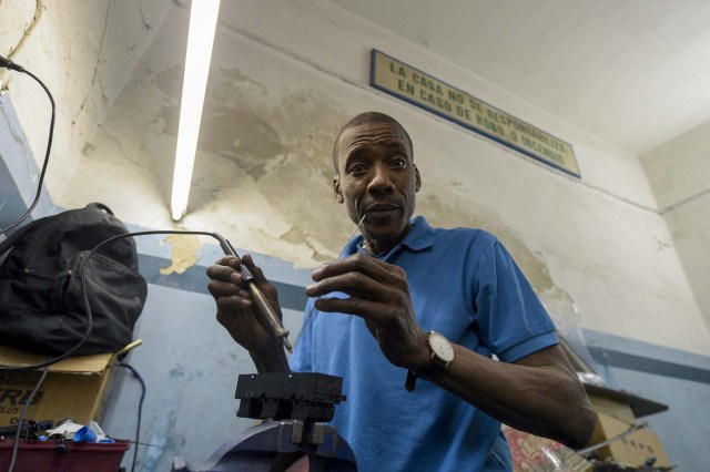 Venezuelan Hugo Alexander works at a locksmith's car shop in Montevideo on May 10, 2018. Exiled Venezuelans have no expectations of the presidential election taking place next May 20 in their home country. / AFP PHOTO / MIGUEL ROJO