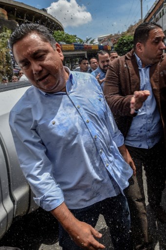 Venezuelan opposition presidential candidate and evangelical pastor Javier Bertucci (L) is thrown water by relatives of prisoners who didn't want candidates doing politics at El Helicoide, the headquarters of the Bolivarian National Intelligence Service (SEBIN), in Caracas, on May 17, 2018, where Venezuelan opponents and a US citizen have seized control of the detention centre. The Venezuelan opponents and a US Mormon missionary, who took control of the cell block area on the eve, are demanding the release of prisoners, according to videos broadcast on social networks. / AFP PHOTO / Juan BARRETO