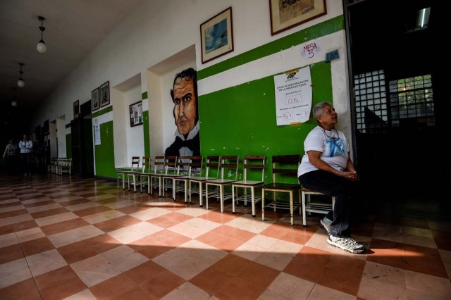 Una mujer venezolana espera en una casilla de votación vacía durante las elecciones presidenciales en Caracas el 20 de mayo de 2018 Los venezolanos, tambaleándose bajo una crisis económica devastadora, comenzaron a votar el domingo en unas elecciones boicoteadas por la oposición y condenadas por gran parte de la comunidad internacional, pero esperaban entregar al profundamente impopular presidente Nicolás Maduro un nuevo mandato / AFP PHOTO / Juan BARRETO