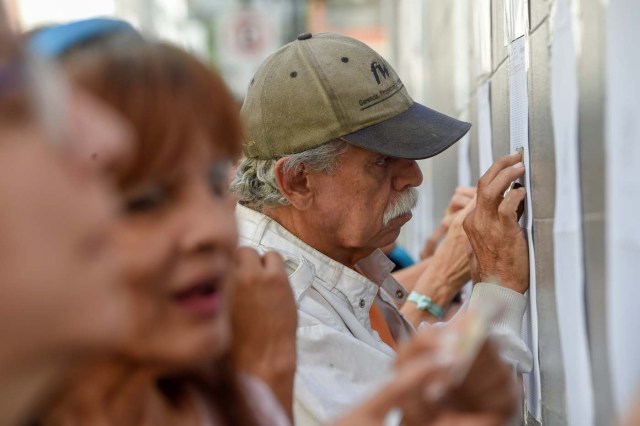 Venezuelans looks for their names at a polling station before casting their vote during presidential elections in Caracas on May 20 Venezuelans, reeling under a devastating economic crisis, began voting Sunday in an election boycotted by the opposition and condemned by much of the international community but expected to hand deeply unpopular President Nicolas Maduro a new mandate / AFP PHOTO / Juan BARRETO