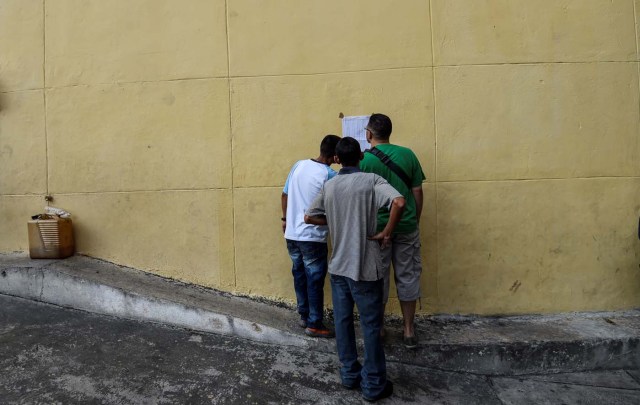 Venezuelans looks for their names at a polling station before casting their vote during the presidential elections in Caracas on May 20 Venezuelans, reeling under a devastating economic crisis, began voting Sunday in an election boycotted by the opposition and condemned by much of the international community but expected to hand deeply unpopular President Nicolas Maduro a new mandate / AFP PHOTO / Juan BARRETO