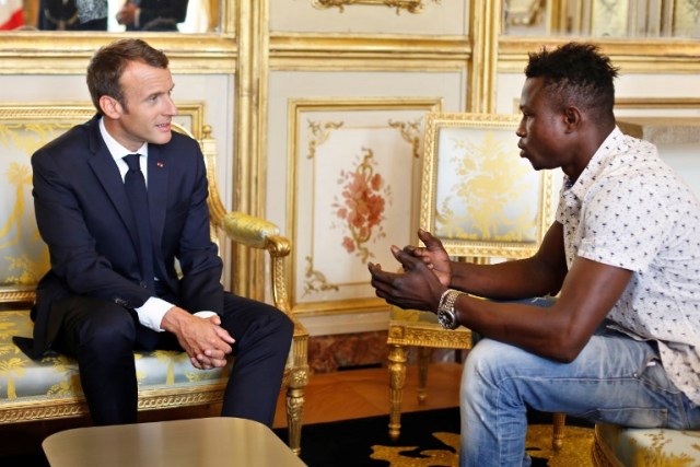 El presidente francés Emmanuel Macron (izq.) Habla con Mamoudou Gassama, de 22 años, de Mali, en el palacio presidencial del Elíseo en París, el 28 de mayo de 2018. Mamoudou Gassama que vive ilegalmente en Francia es honrado por Macron por escalar un edificio de apartamentos durante el fin de semana para salvar a un niño de 4 años que cuelga de un balcón en el quinto piso. / AFP PHOTO / POOL / Thibault Camus