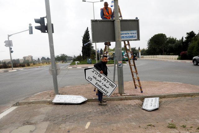 Un trabajador sostiene un letrero que dirige a la embajada de los EE. UU., En el área del consulado de EE. UU. En Jerusalén, el 7 de mayo de 2018. REUTERS / Ronen Zvulun / File Photo