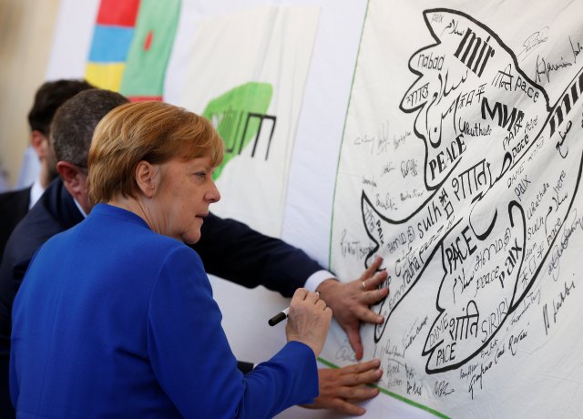 La canciller alemana, Angela Merkel, firma una bandera de la paz durante su visita a Asís, Italia, el 12 de mayo de 2018. REUTERS / Yara Nardi 