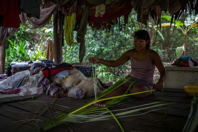 Fotografía fechada el 10 de mayo de 2018 que muestra a una mujer de la etnia Warao mientras deshenebra una palma de Morichal, en Maturín (Venezuela). Unos 120 indígenas distribuidos en cerca de 30 palafitos de precaria elaboración conforman la comunidad de Morichal Largo, un asentamiento de la etnia Warao ubicado en el sur de Venezuela, que resiste debajo de un puente la miseria e insalubridad propia de la crisis nacional. EFE/Cristian Hernández