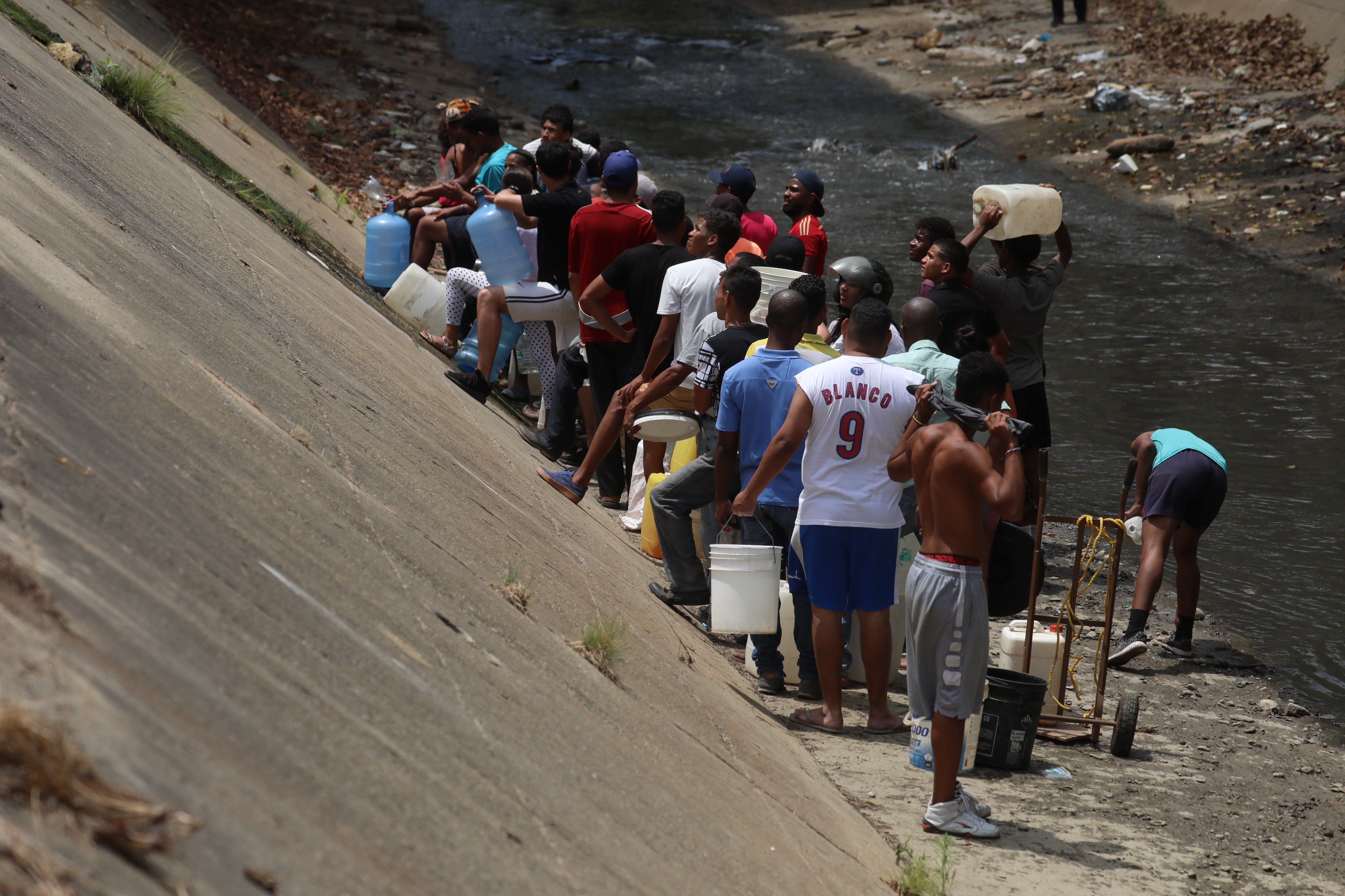 A falta de agua: Caraqueños recogen agua en río contaminado debido a la escasez por el apagón (Fotos)