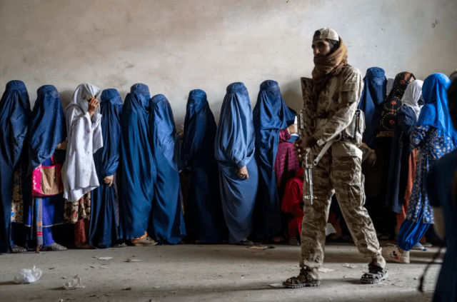En esta imagen de archivo, un combatiente talibán hace guardia mientras un grupo de mujeres espera para recibir comida de un grupo de ayuda humanitaria, en Kabul, Afganistán (AP Foto/Ebrahim Noroozi)